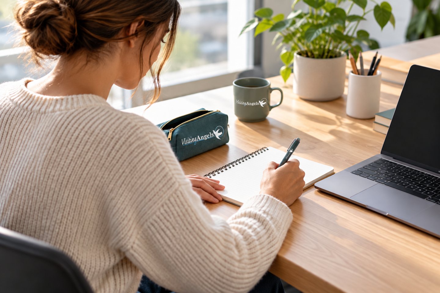 An employee taking notes beside a branded mug and pouch at a first-week workstation.