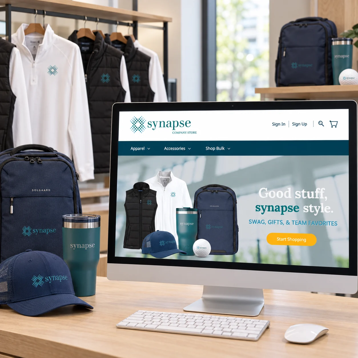 Synapse online company store on a desktop monitor alongside matching branded apparel and an in-person merchandise display